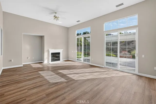 a view of an empty room with window and wooden floor