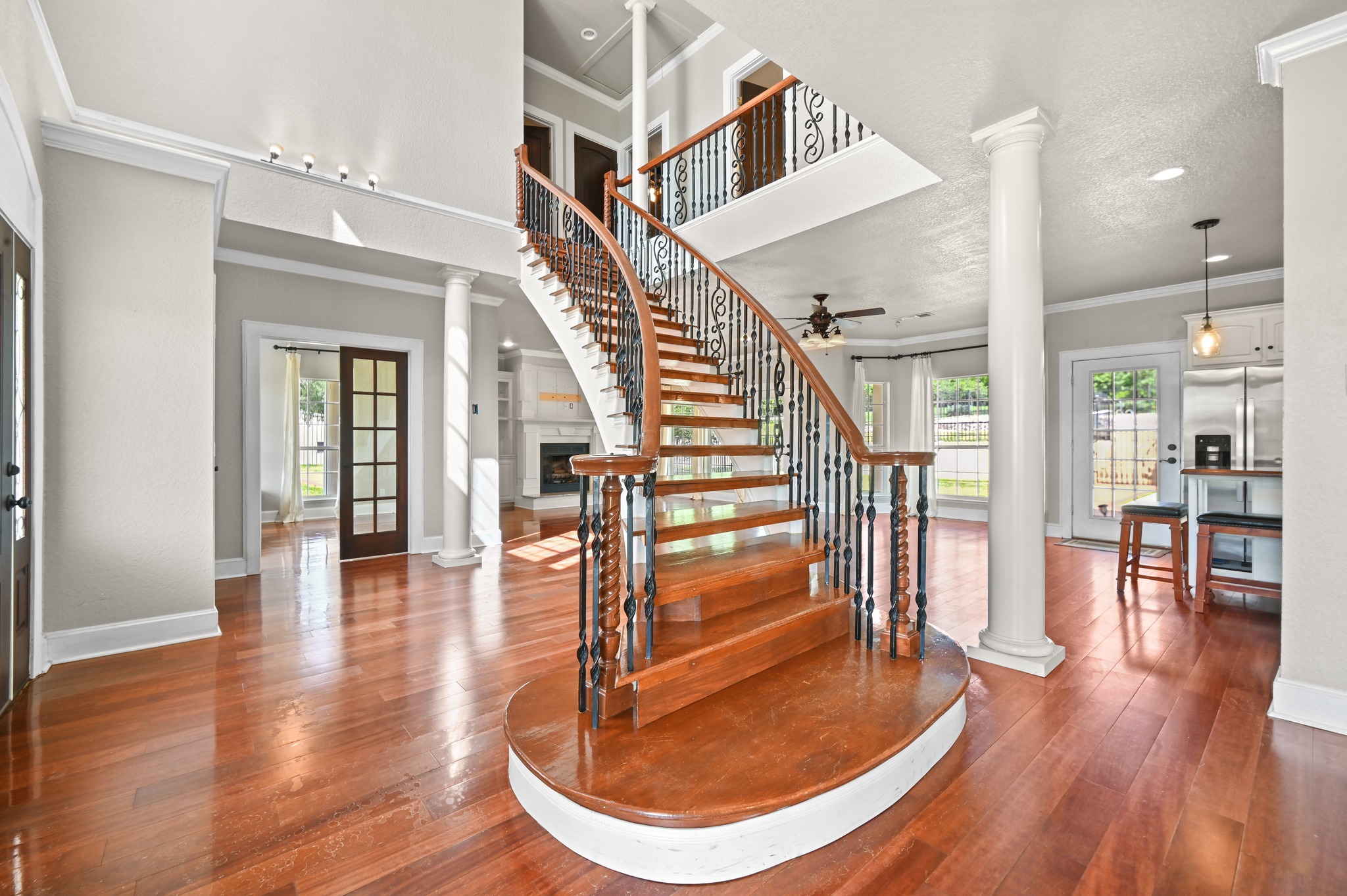 1175 Southern Way Luling, TX 78648 - Photo 14 of 40 A grand, curved staircase with ornate iron balusters anchors this elegant foyer featuring rich hardwood floors and recessed lighting.