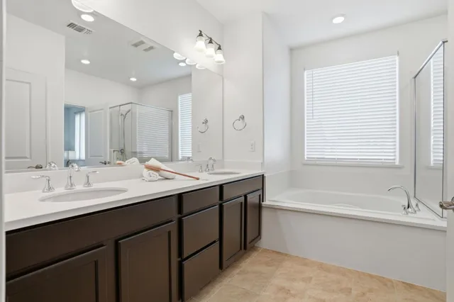 a bathroom with a double vanity sink mirror and a bathtub