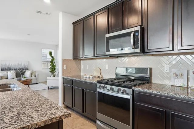 a kitchen with stainless steel appliances granite countertop a stove a sink and a microwave
