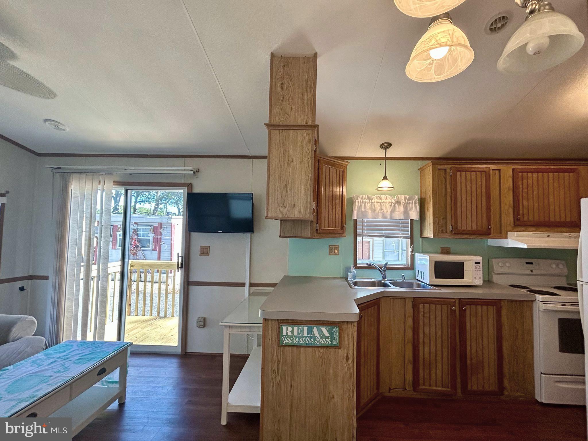 104 South 5th Avenue, Unit 39 Rio Grande, NJ 08242 - Photo 7 of 20 a kitchen with granite countertop a refrigerator a stove a sink dishwasher and wooden cabinets with wooden floor