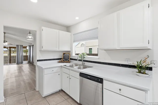 a kitchen with a sink dishwasher and white cabinets with wooden floor