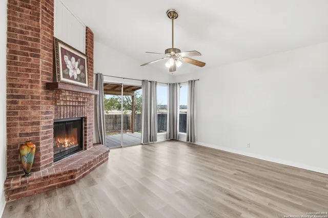 a view of a livingroom with a fireplace a ceiling fan and brick wall
