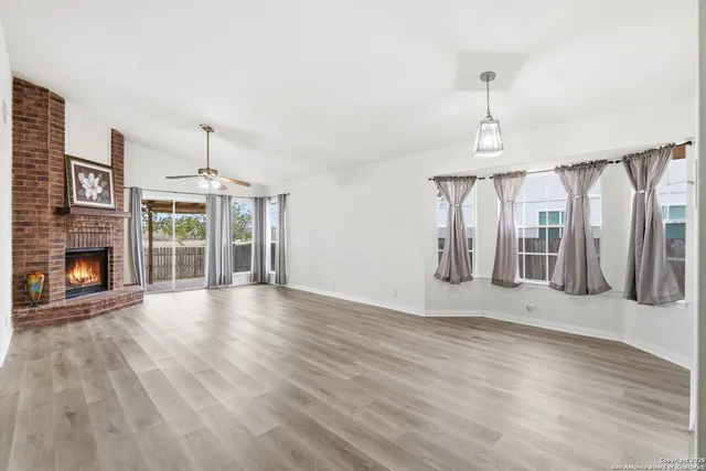 a view of an empty room with wooden floor fireplace and a window