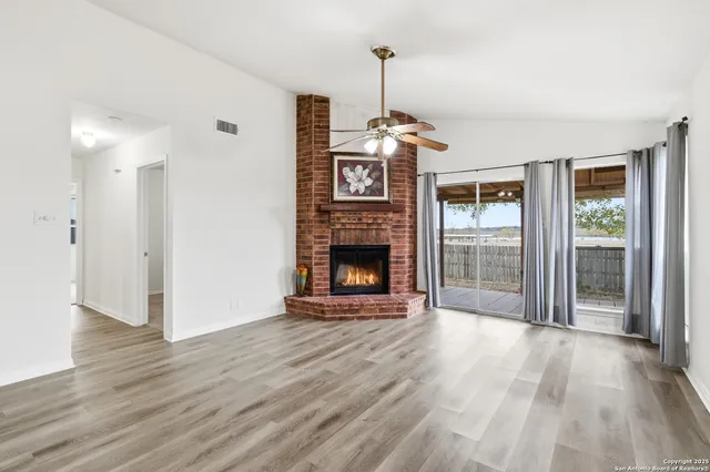 a view of a livingroom with wooden floor a fireplace and a window