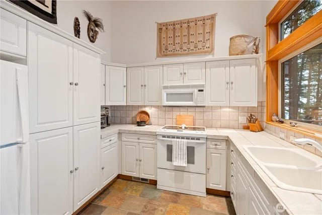 a kitchen with granite countertop white cabinets and white appliances