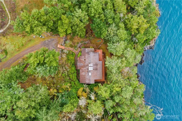 an aerial view of residential house with outdoor space and trees all around