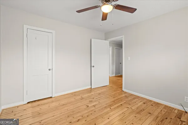 an empty room with wooden floor and fan