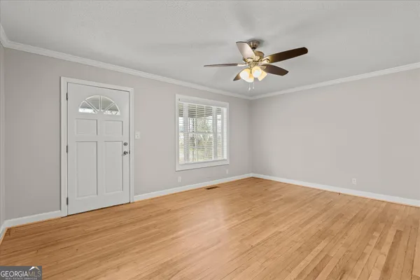 a view of empty room with wooden floor and fan