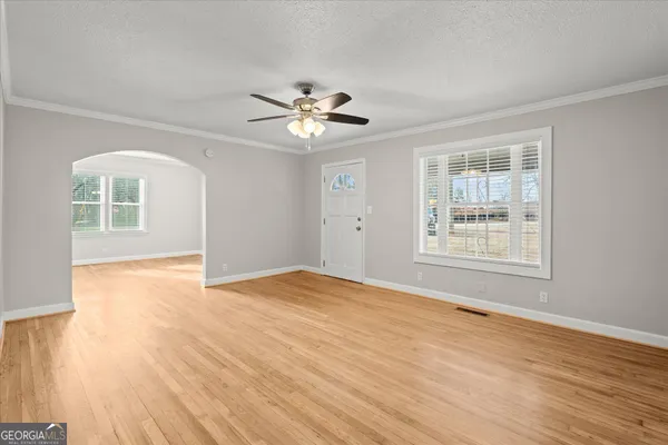 a view of an empty room with a window and wooden floor
