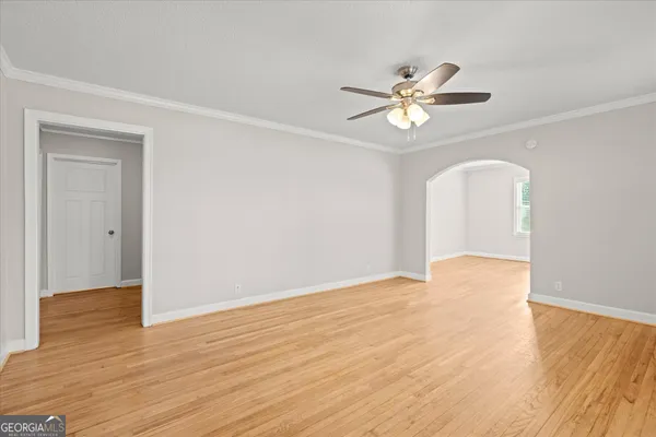 a view of an empty room with chandelier fan and wooden floor