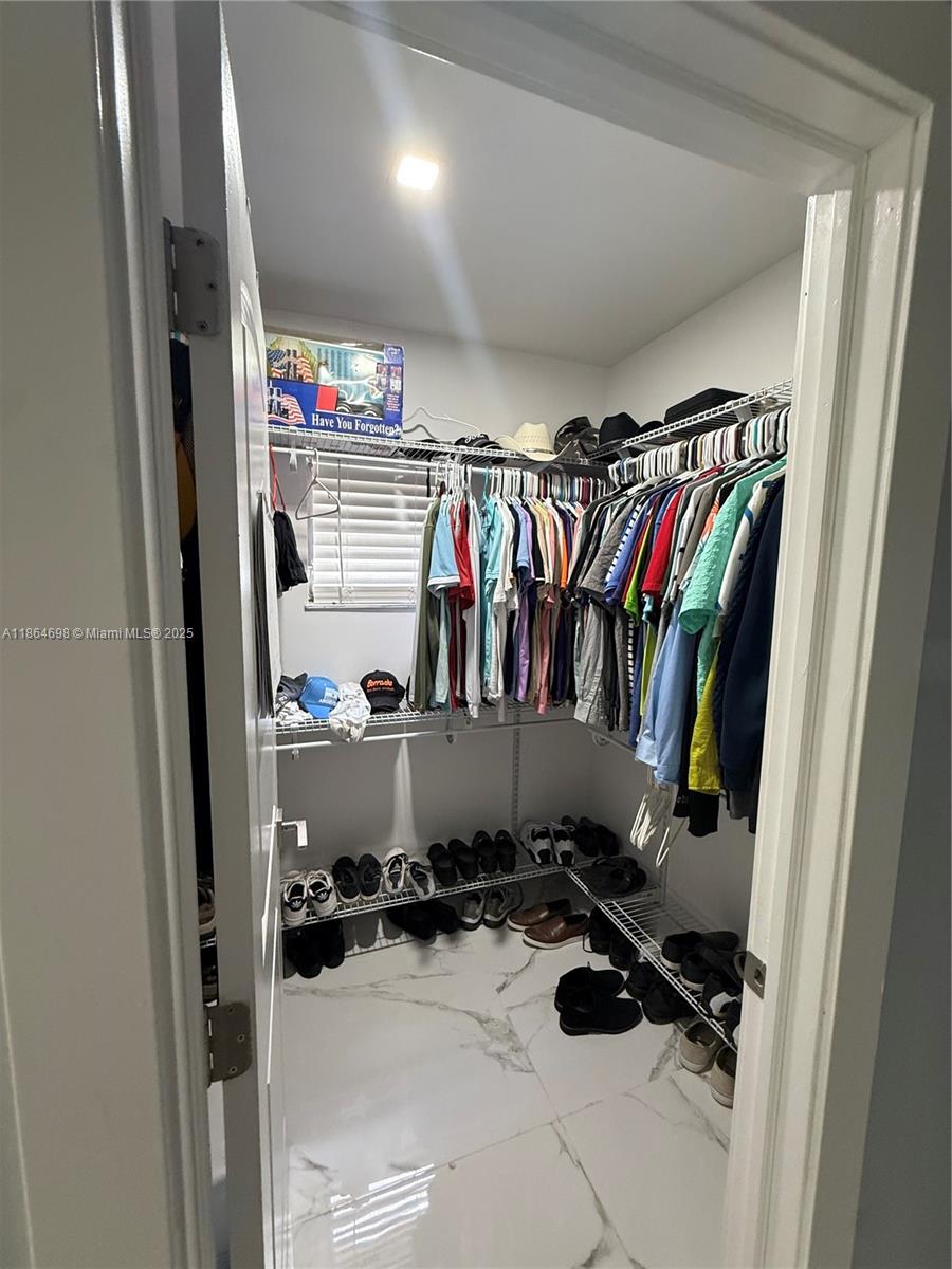 15765 Southwest 206th Avenue Miami, FL 33187 - Photo 55 of 57 a view of walk in closet with clothes and shoes