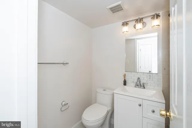 a bathroom with a toilet sink vanity and mirror