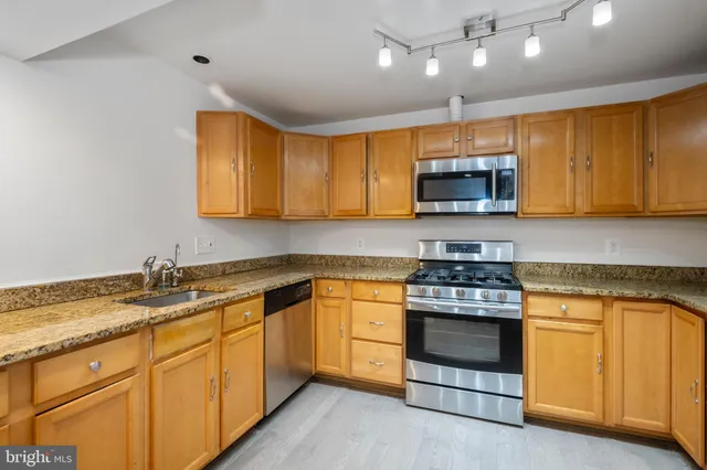a kitchen with stainless steel appliances granite countertop a stove a sink and a microwave