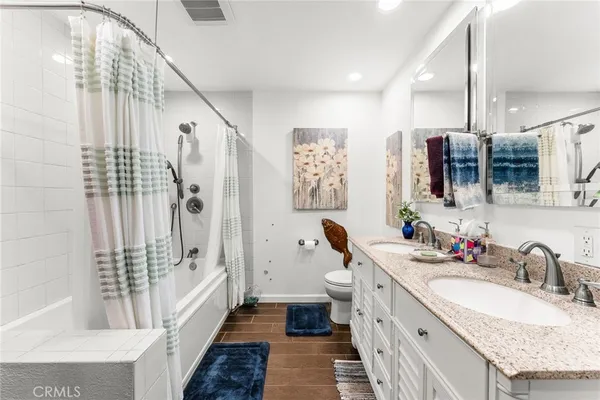 a kitchen with stainless steel appliances granite countertop a refrigerator a sink dishwasher a stove and a dining table with wooden floor