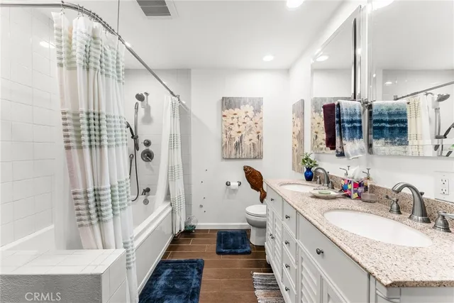 a kitchen with stainless steel appliances granite countertop a refrigerator a sink dishwasher a stove and a dining table with wooden floor