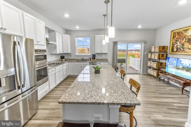 a large kitchen with stainless steel appliances granite countertop a stove refrigerator and wooden floor