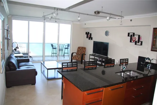a view of a dining room with furniture a kitchen and chandelier