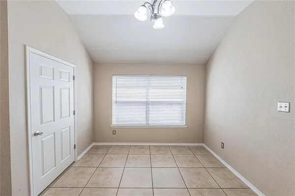 an empty room with chandelier fan and windows