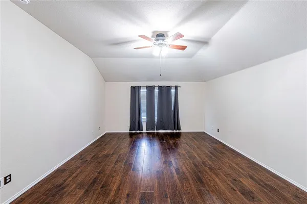 an empty room with wooden floor chandelier fan and windows