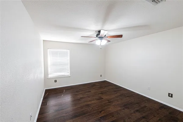 an empty room with wooden floor fan and windows