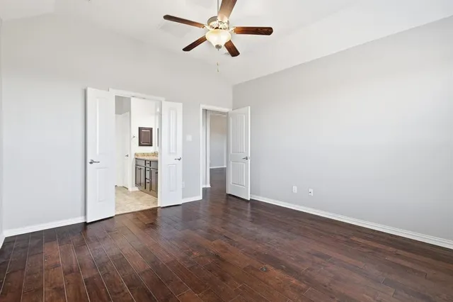 an empty room with wooden floor chandelier fan and windows