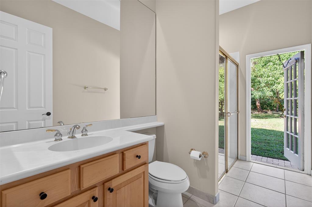 15601 Southwest 15th Street Davie, FL 33326 - Photo 38 of 52 a bathroom with a granite countertop sink a toilet a mirror and a shower