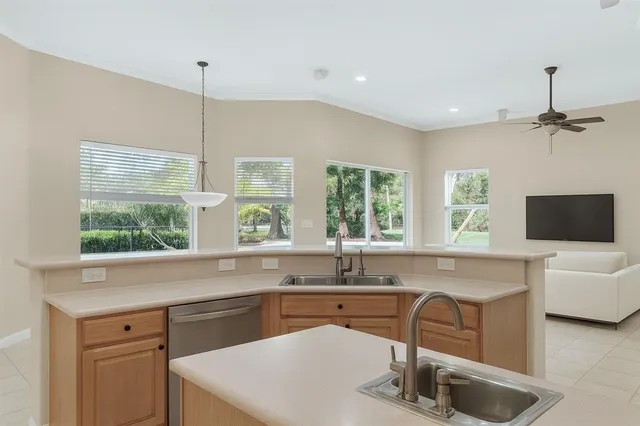 a kitchen with a sink a counter top space and living room view
