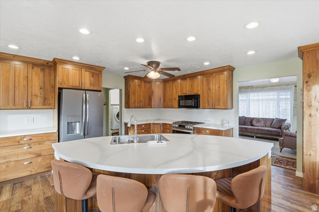 165 Main Street Georgetown, ID 83239 - Photo 12 of 50 Kitchen featuring a kitchen breakfast bar, appliances with stainless steel finishes, brown cabinetry, dark wood-style flooring, and recessed lighting