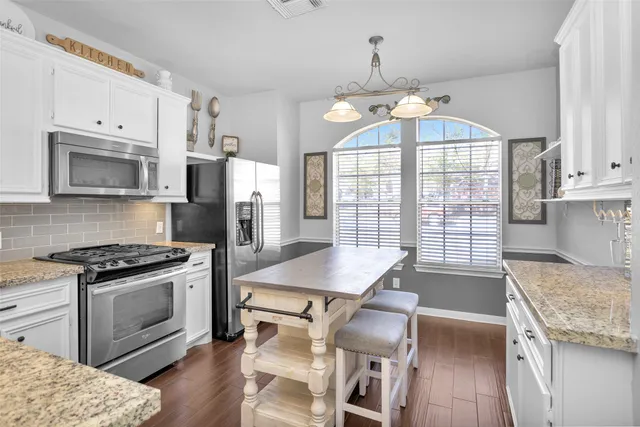 a kitchen with granite countertop white cabinets and stainless steel appliances