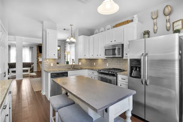 a kitchen with white cabinets a sink dishwasher and a stove with wooden floor