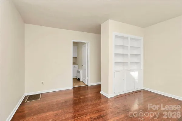 a view of an empty room with a window and wooden floor