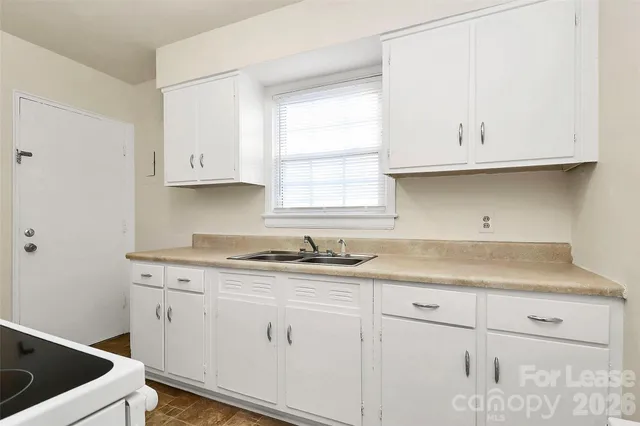 a kitchen with granite countertop white cabinets and a sink