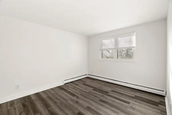 an empty room with a wooden floor and windows