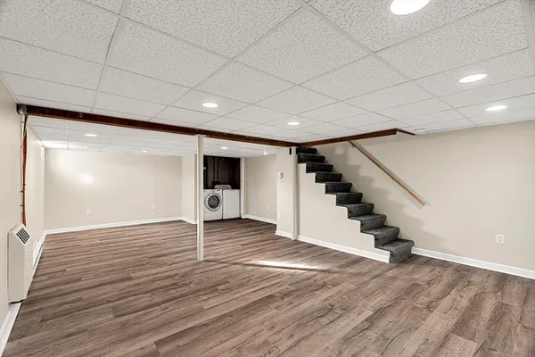 a view of an empty room with wooden floor and stairs