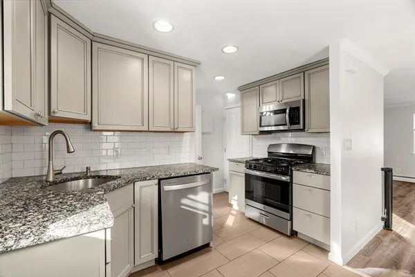 a kitchen with stainless steel appliances granite countertop a stove a sink and a microwave