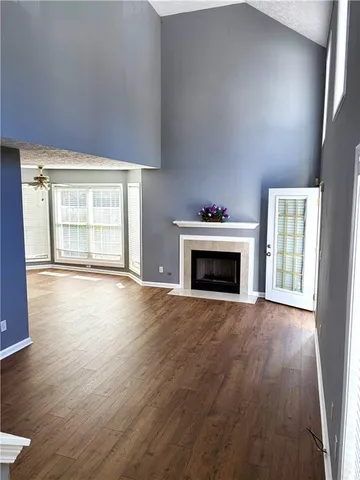 an empty room with wooden floor fireplace and windows