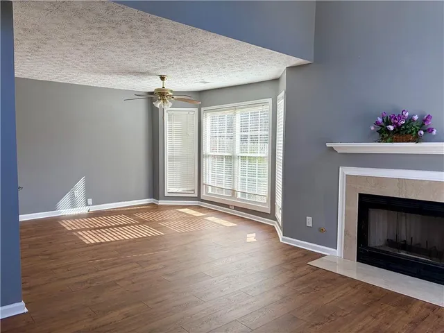 a view of an empty room with wooden floor fireplace and a window