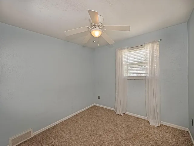 an empty room with windows and fan