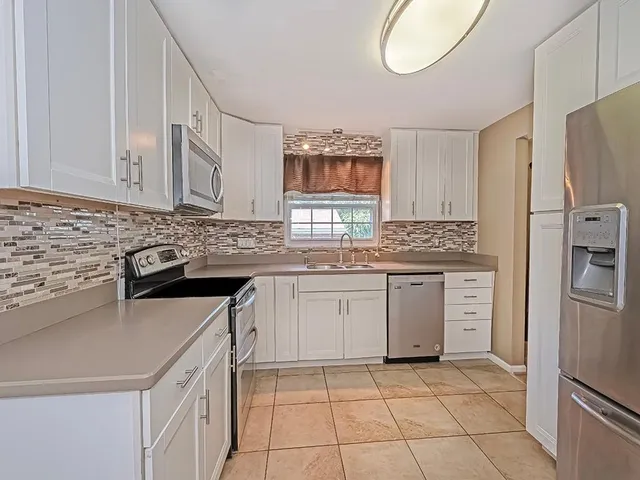a kitchen with granite countertop a sink appliances and cabinets