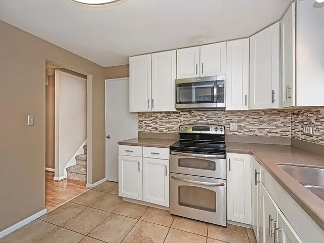 a kitchen with granite countertop white cabinets and stainless steel appliances