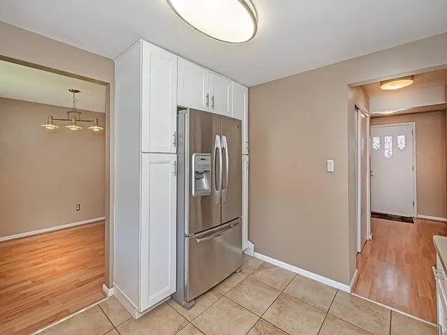 a view of a refrigerator in kitchen and an empty room