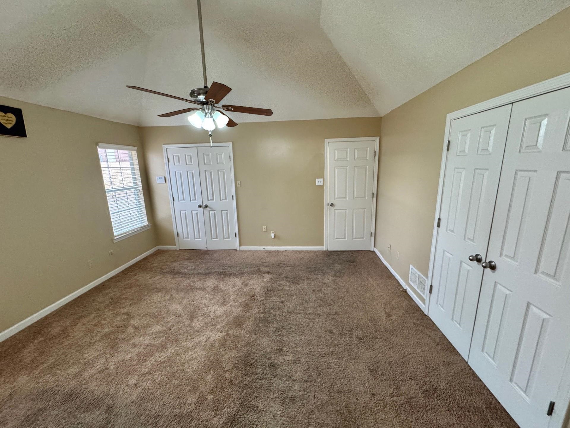 76 Autumn Branch Lane Memphis, TN 38109 - Photo 11 of 13 Unfurnished bedroom with carpet flooring, multiple closets, ceiling fan, a textured ceiling, and lofted ceiling