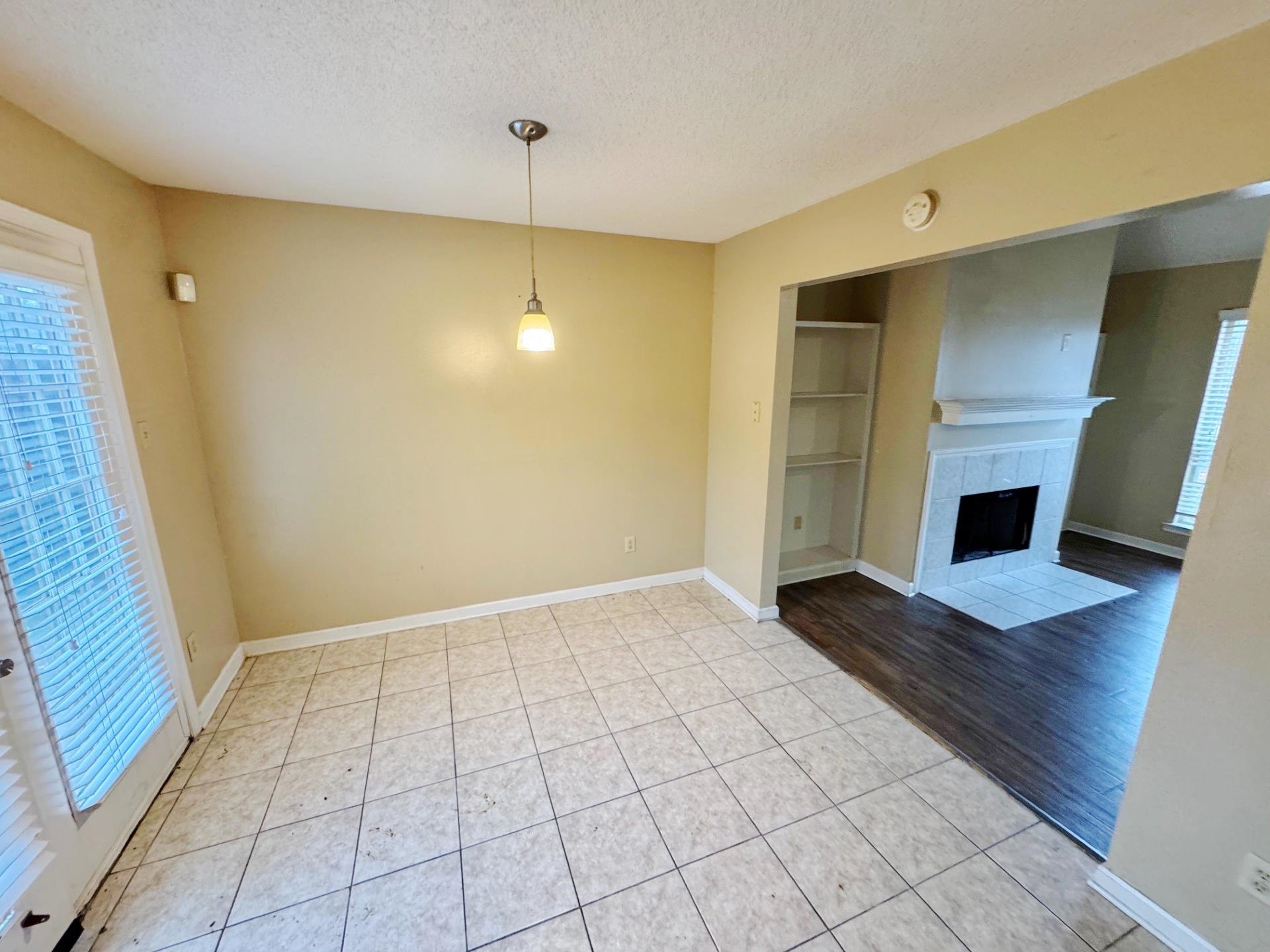 76 Autumn Branch Lane Memphis, TN 38109 - Photo 3 of 13 Unfurnished living room featuring a tile fireplace, light tile patterned floors, and a textured ceiling