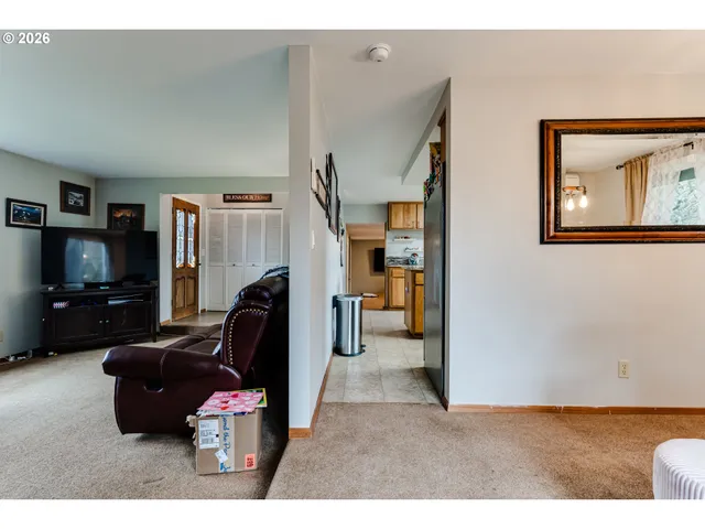 a living room with furniture a flat screen tv and a refrigerator