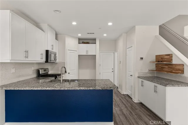 a kitchen with granite countertop stainless steel appliances a sink counter top space and cabinets