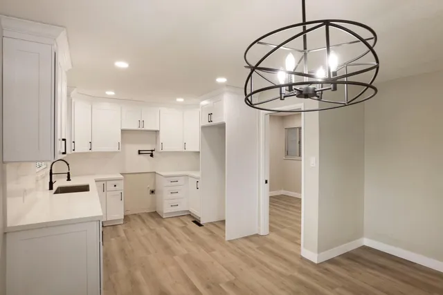 a kitchen with kitchen island stainless steel appliances a sink cabinets and wooden floor