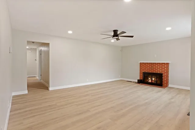 a view of an empty room with a fireplace and a chandelier fan
