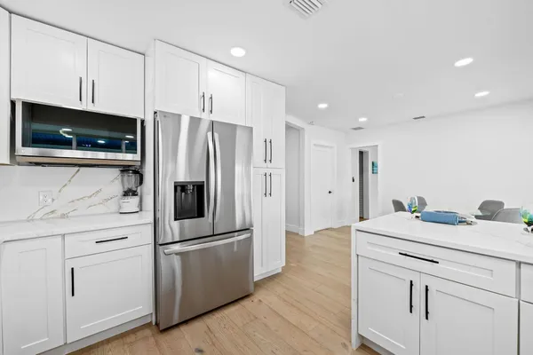 a kitchen with stainless steel appliances a stove a sink dishwasher a refrigerator and a dining table with wooden floor