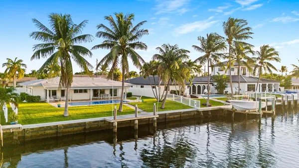a view of a swimming pool with a lawn chairs under palm trees